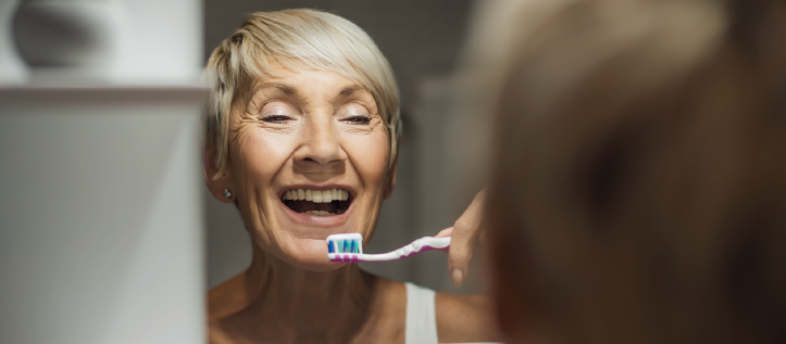 A older woman brushing her teeth to avoid bad breath