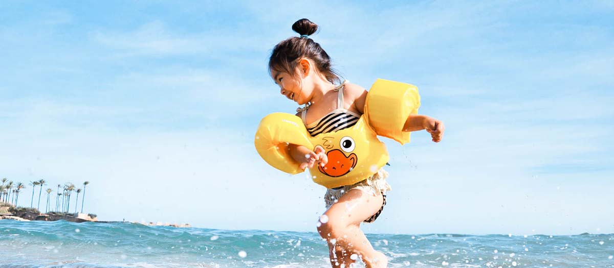 Girl playing in the water at the beach with floaties