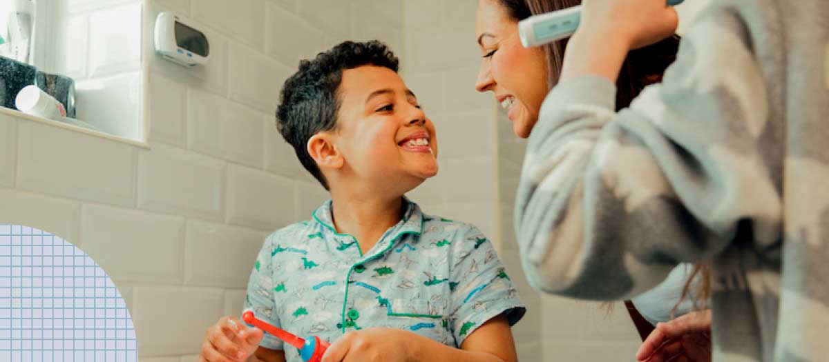 Boy brushing teeth with his mom in bathroom