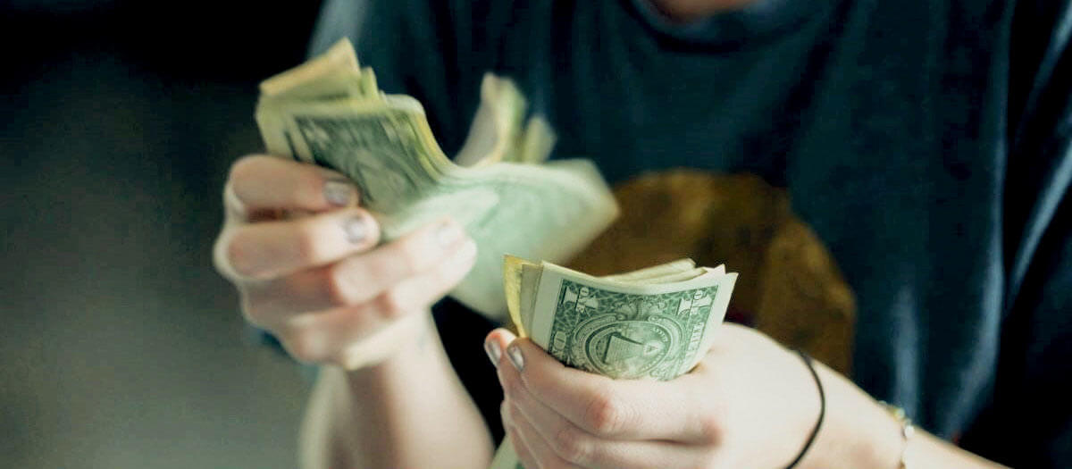 Woman counting money to pay for birdgework