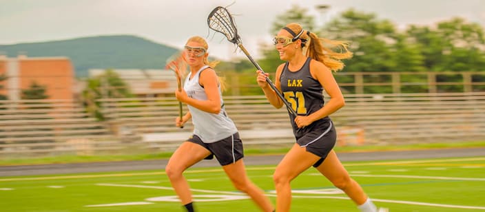 Two teenage girls playing high school lacrosse