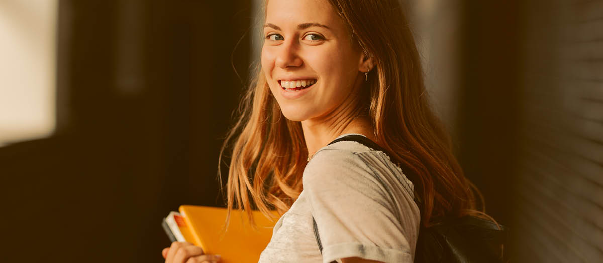 Young student holding books in hallway