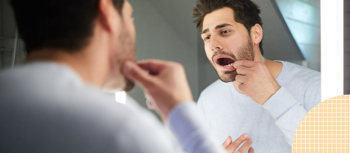 Man checking out his teeth in the mirror