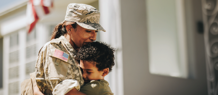 A soldier hugs their child beneath an American flag