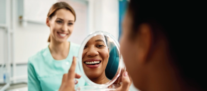 A young woman at the dentist looking at her teeth after a cleaning