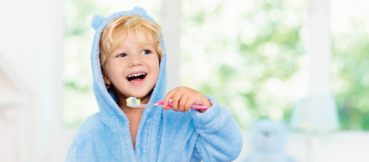 A toddler boy brushing his teeth and smiling