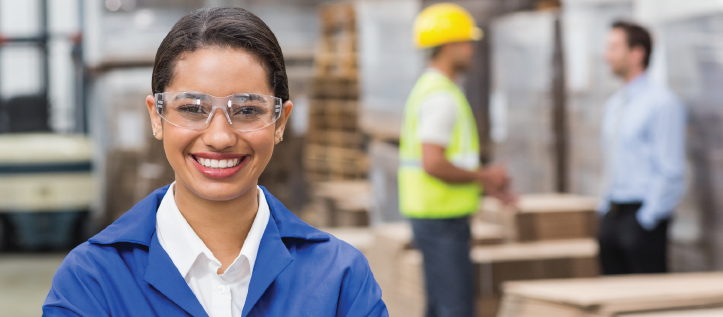 A woman smiling while wearing eye protection glasses at work