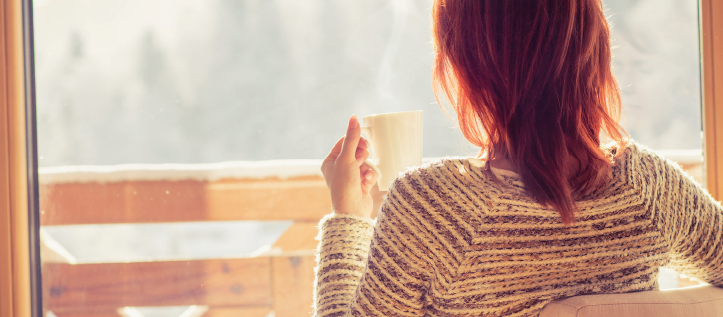 Woman holding a coffee mug looking outside