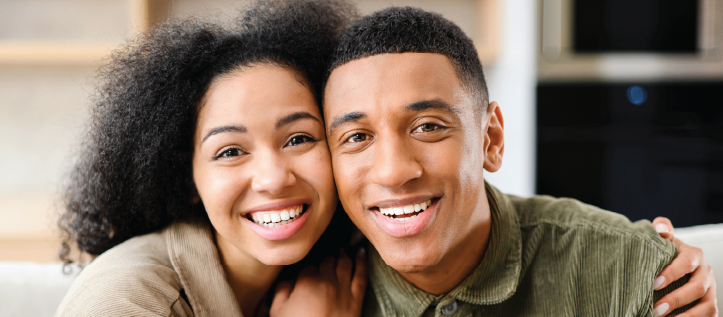 A young couple smiling while sitting in their living room.