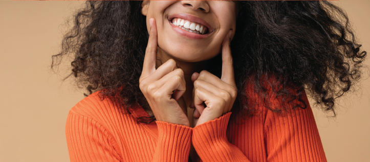 A young woman smiling and pointing at her teeth