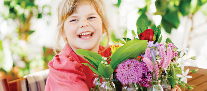 A young child smiling while holding flowers