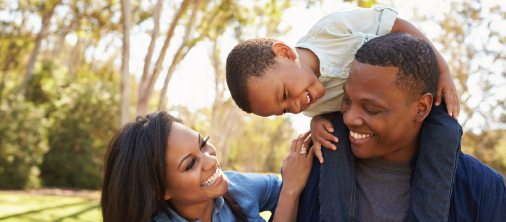 A young family smiling outside