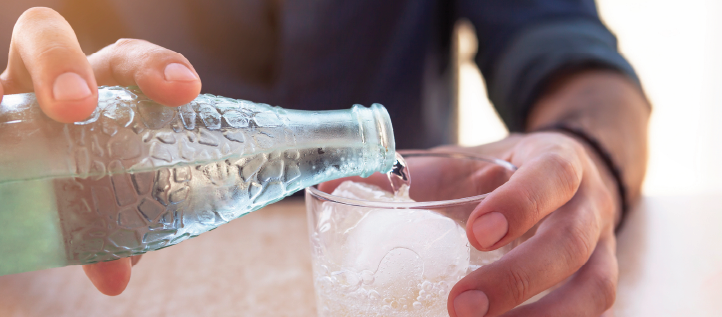 Person pouring sparkling water into a cup