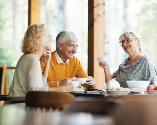 A group of seniors enjoying coffee while smiling and chatting.