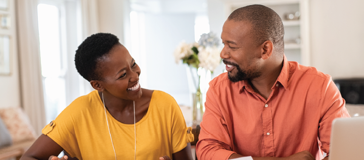 A couple smiling at each other while looking over dental plans.