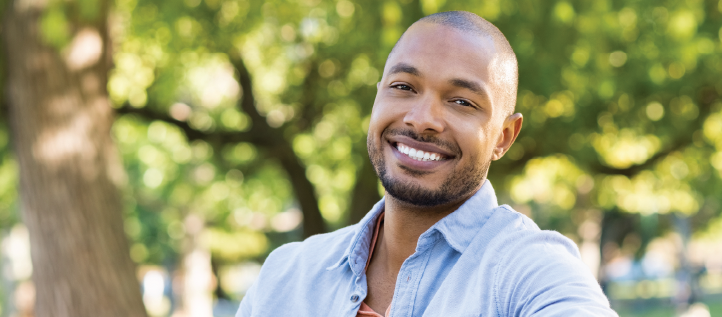 A man smiling sitting on a park bench