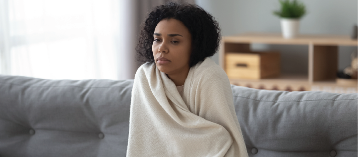 A young woman wrapped up in a blanket feeling ill