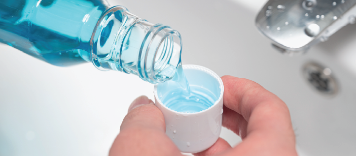 Person pouring mouthwash into a cap