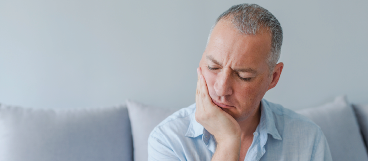 A middle age man holding his jaw in pain after breaking a tooth